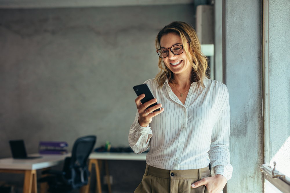 lady smiling while looking at her smartphone